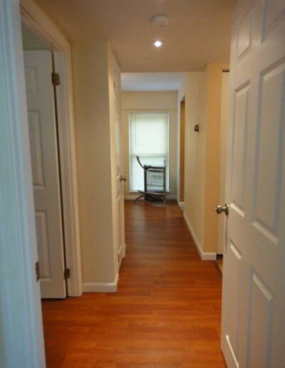 A hallway with white doors and hardwood floors.