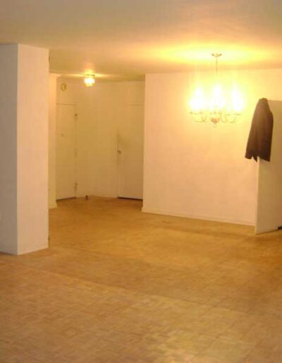 An empty living room with hardwood floors and a chandelier.