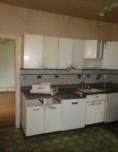 An abandoned kitchen with a stove and sink.