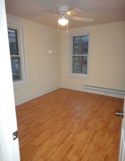 An empty room with hardwood floors and a ceiling fan.